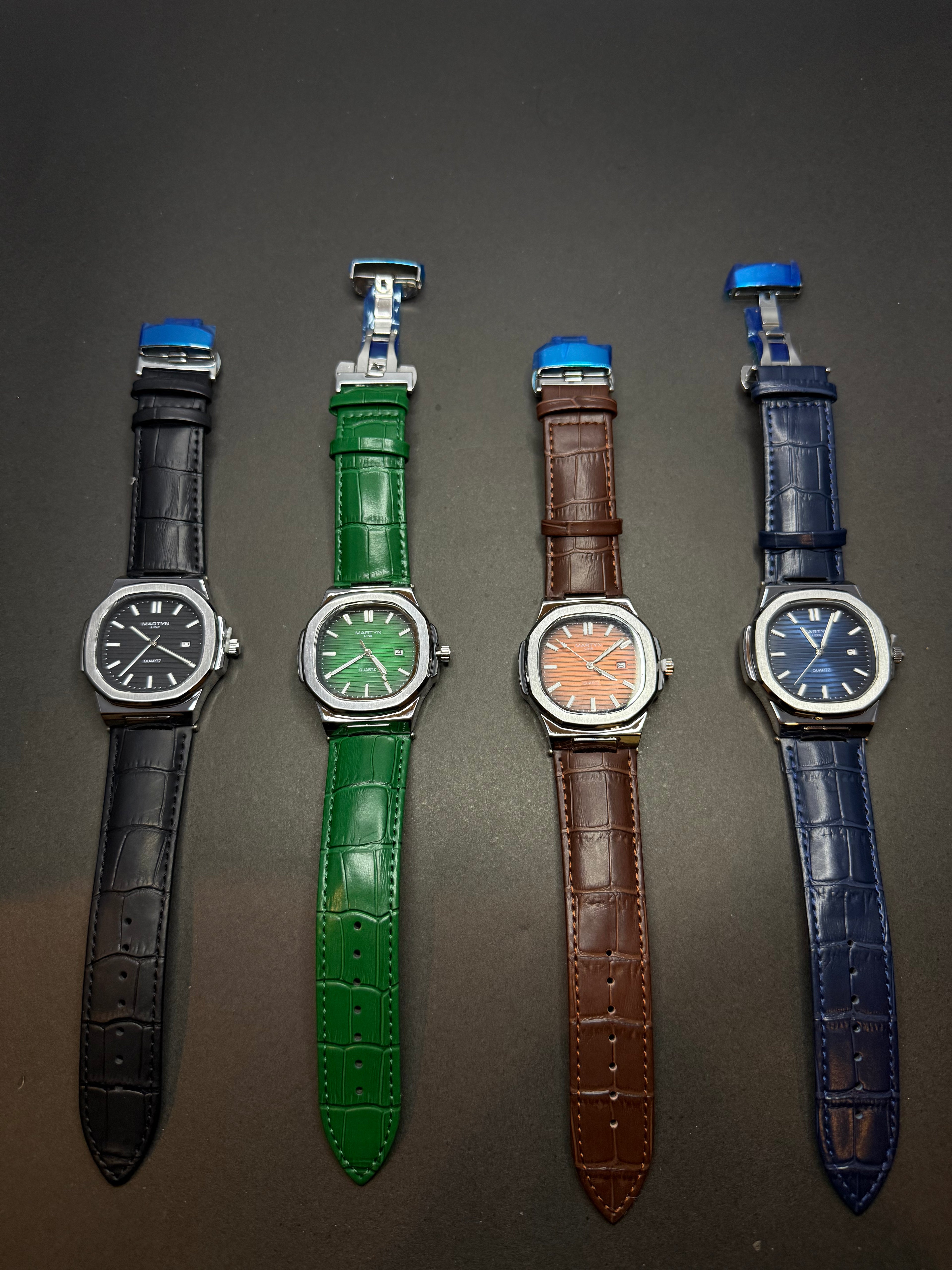 Four watches with different colored straps on a dark surface Martin collection color editions luxury watch premium timepiece Pakistan